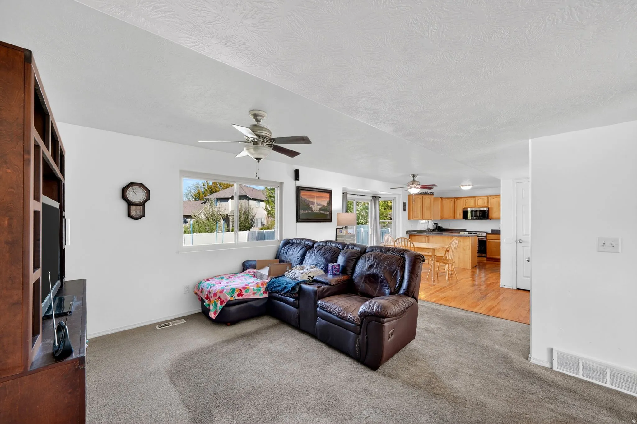 Living area featuring light colored carpet and ceiling fan
