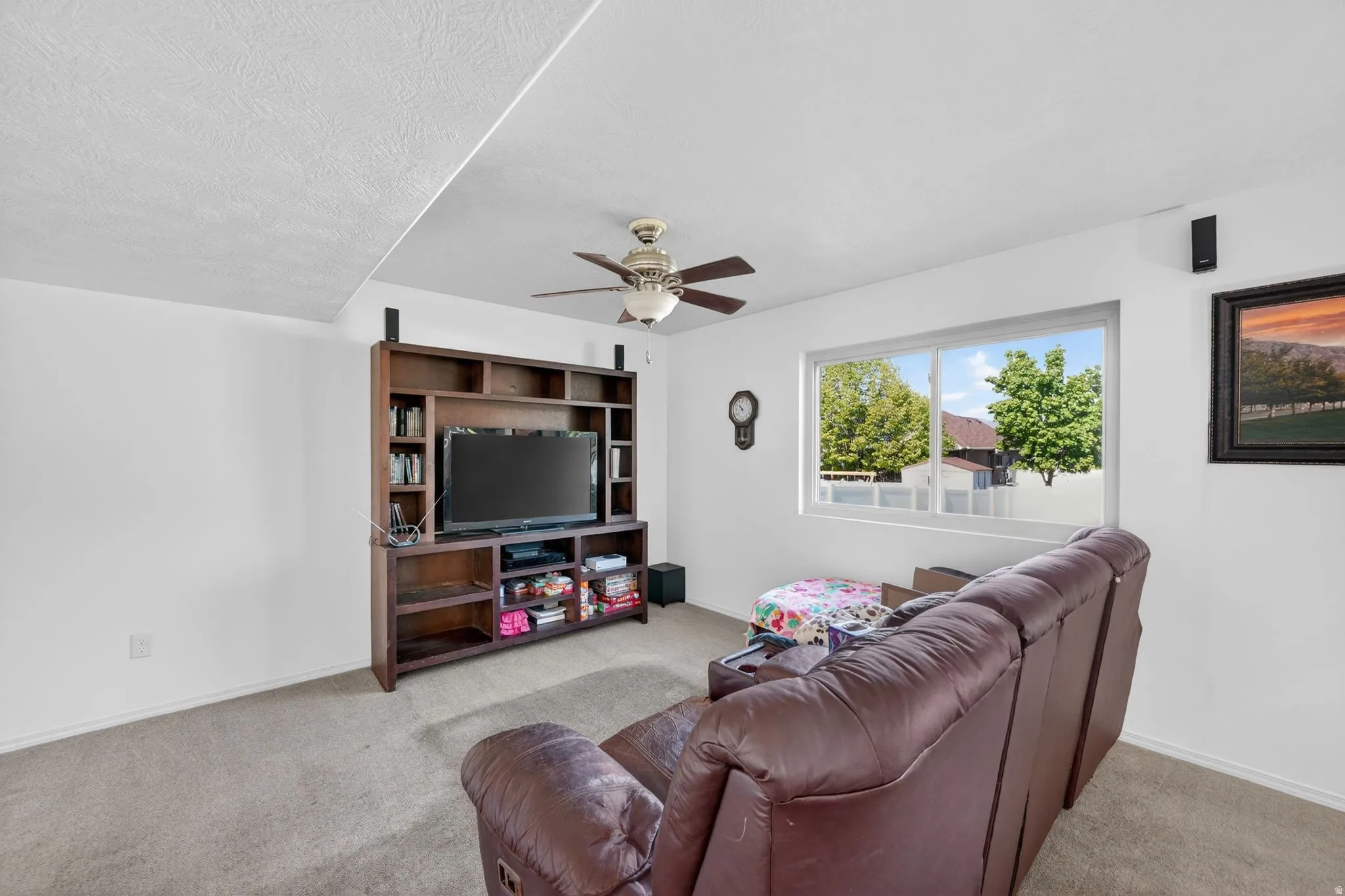Living room featuring ceiling fan, carpet flooring, and a textured ceiling