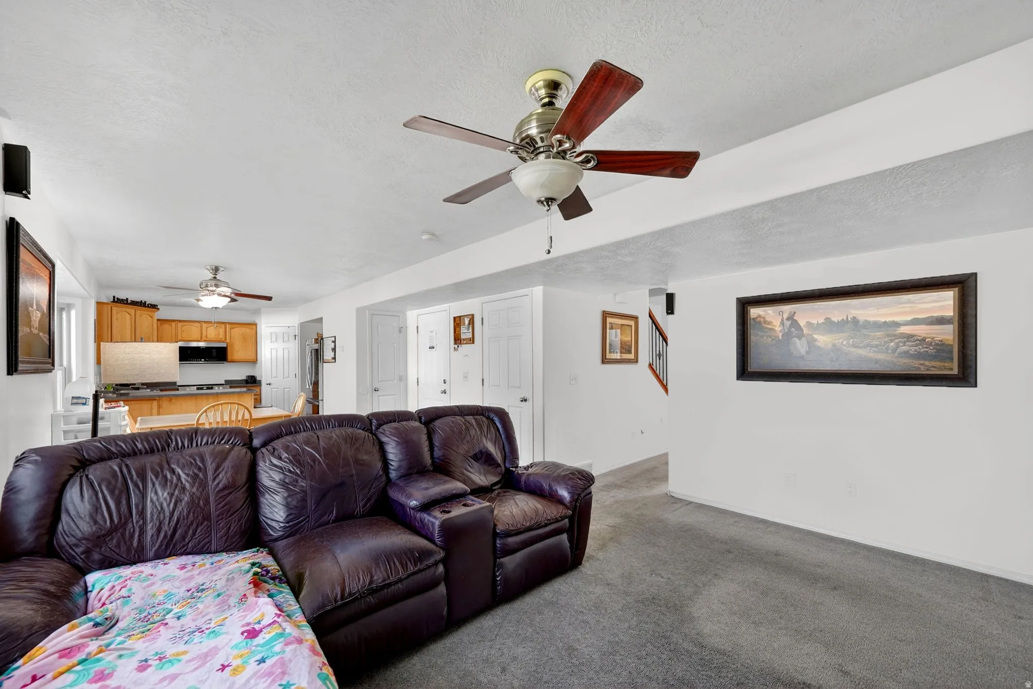 Living area featuring a ceiling fan, a textured ceiling, and light carpet