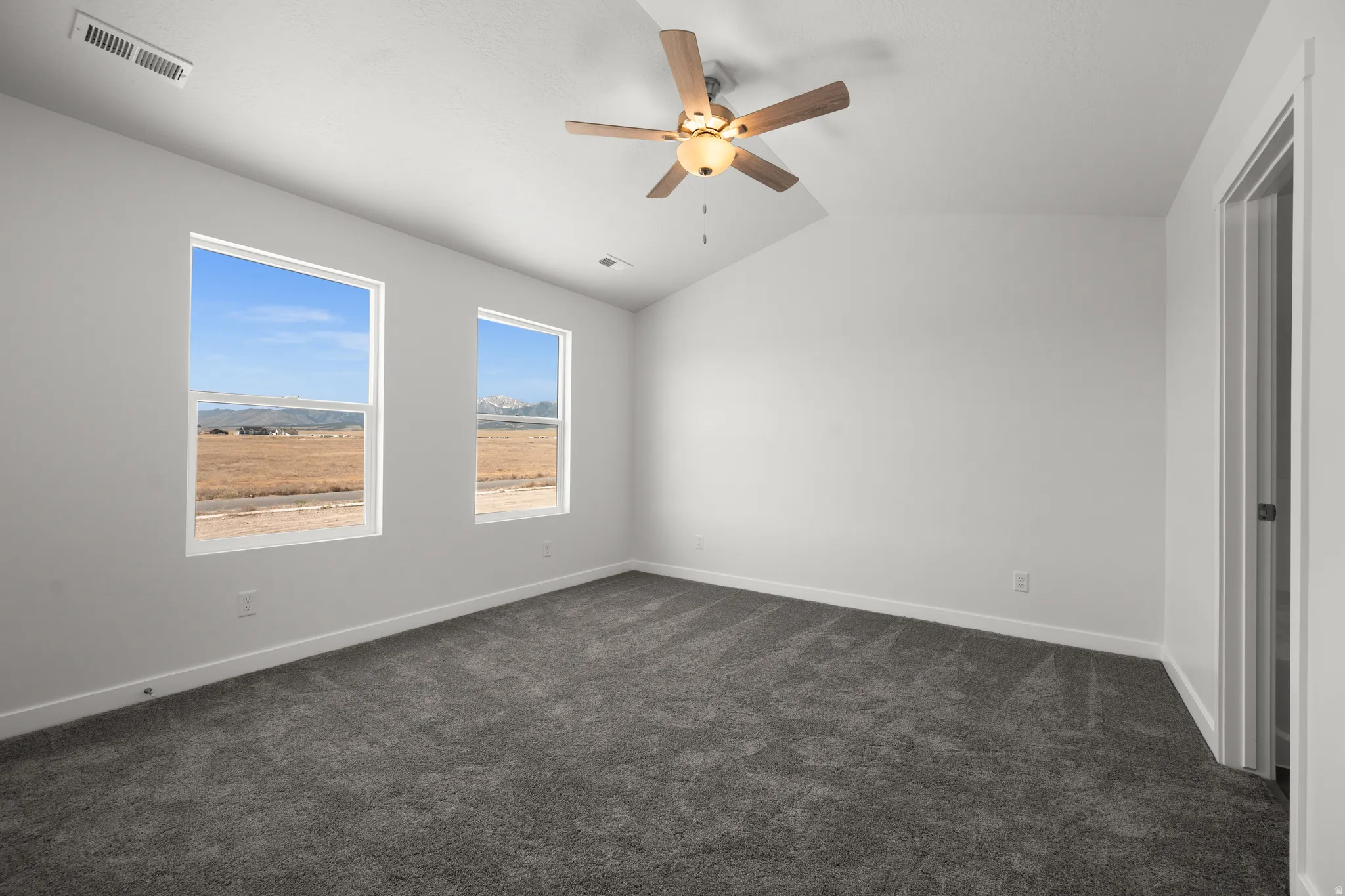 Unfurnished bedroom with lofted ceiling, dark colored carpet, and ceiling fan