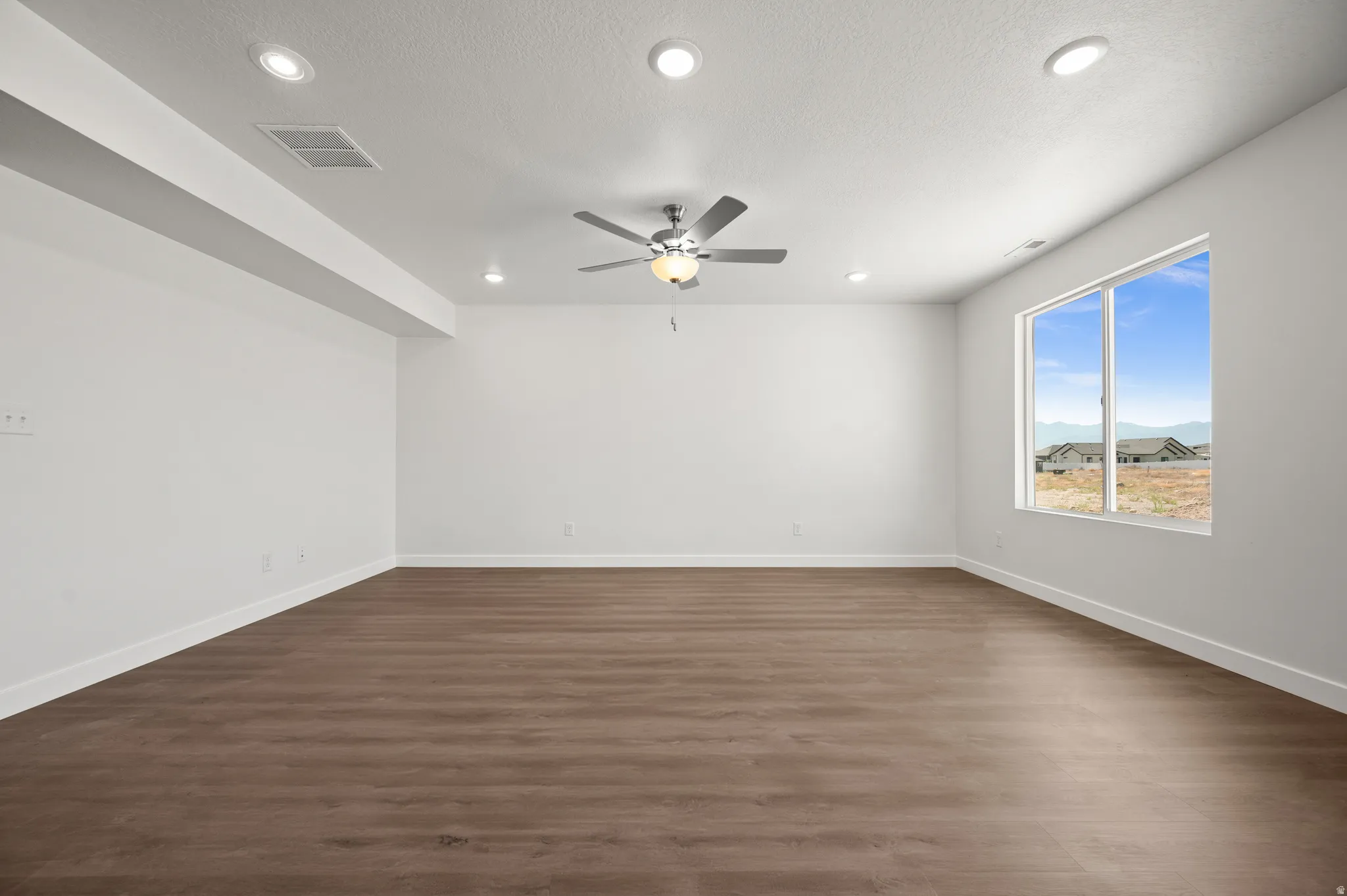 Spare room featuring dark wood-type flooring, a ceiling fan, and recessed lighting