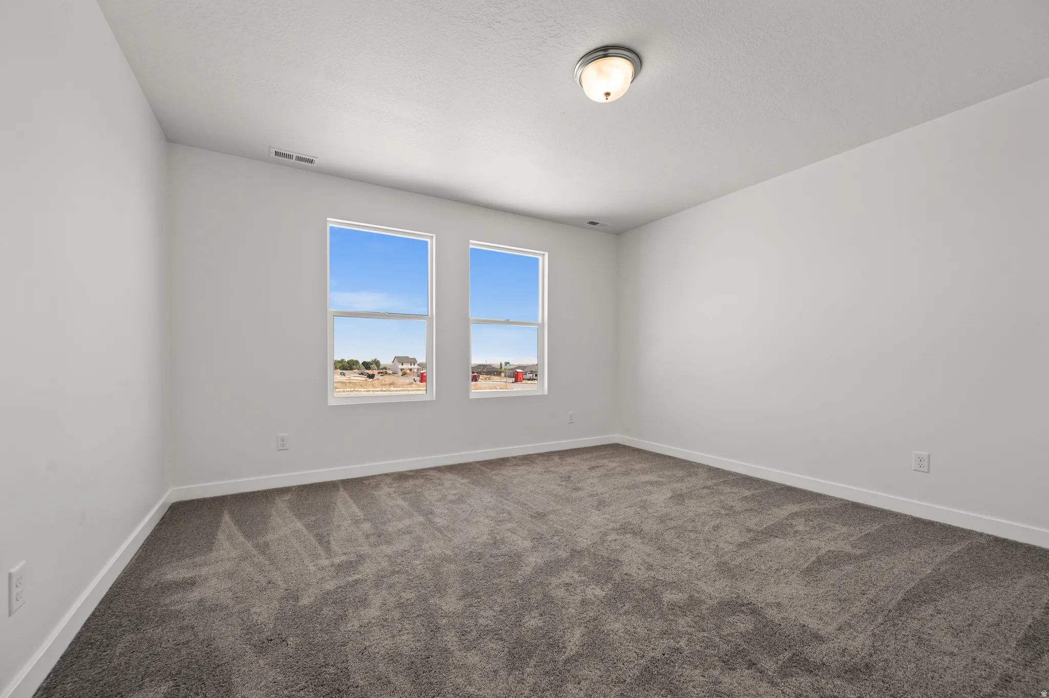 Unfurnished room featuring baseboards and dark carpet