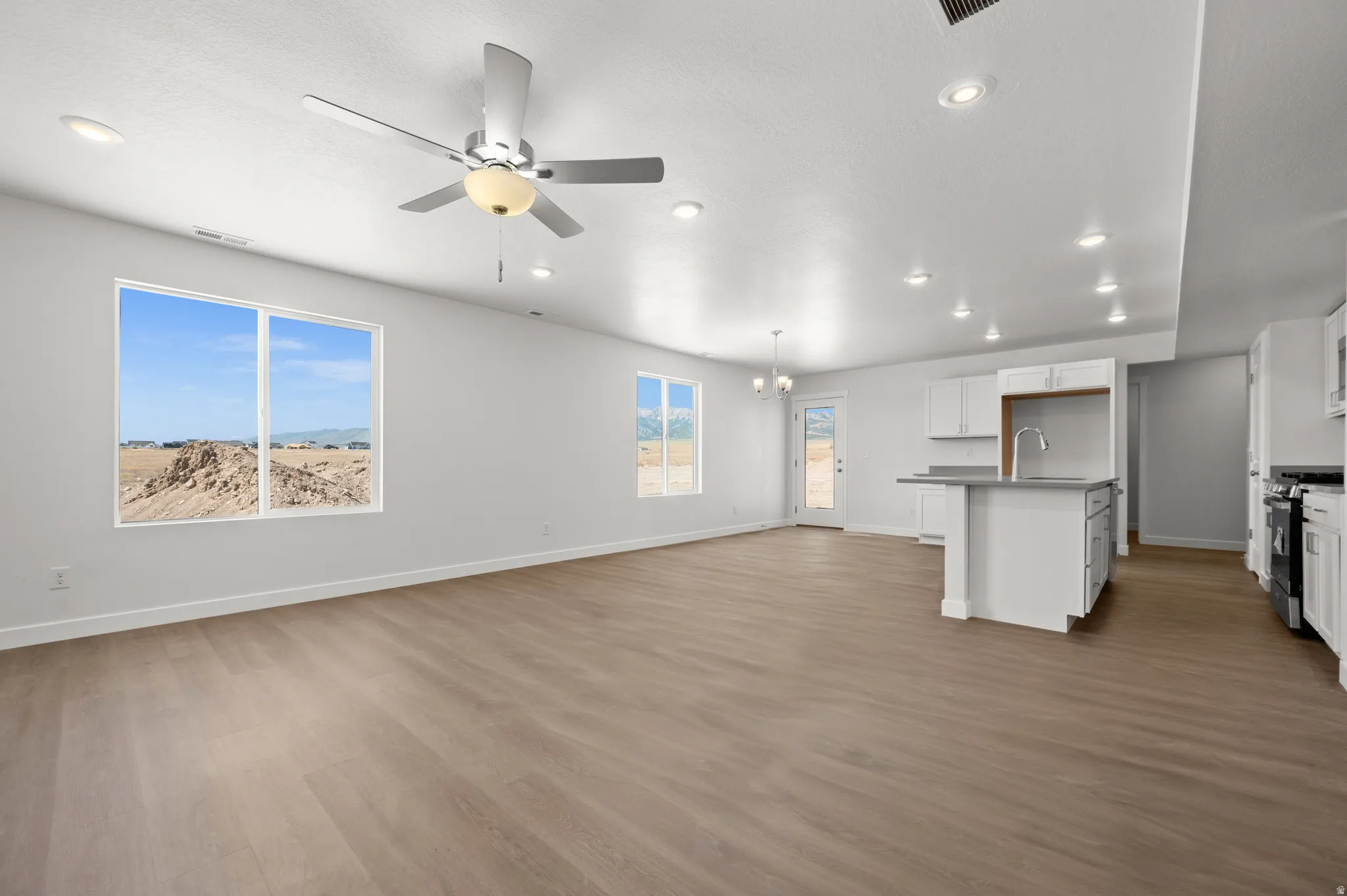 Unfurnished living room featuring a ceiling fan, dark wood-style flooring, and a chandelier