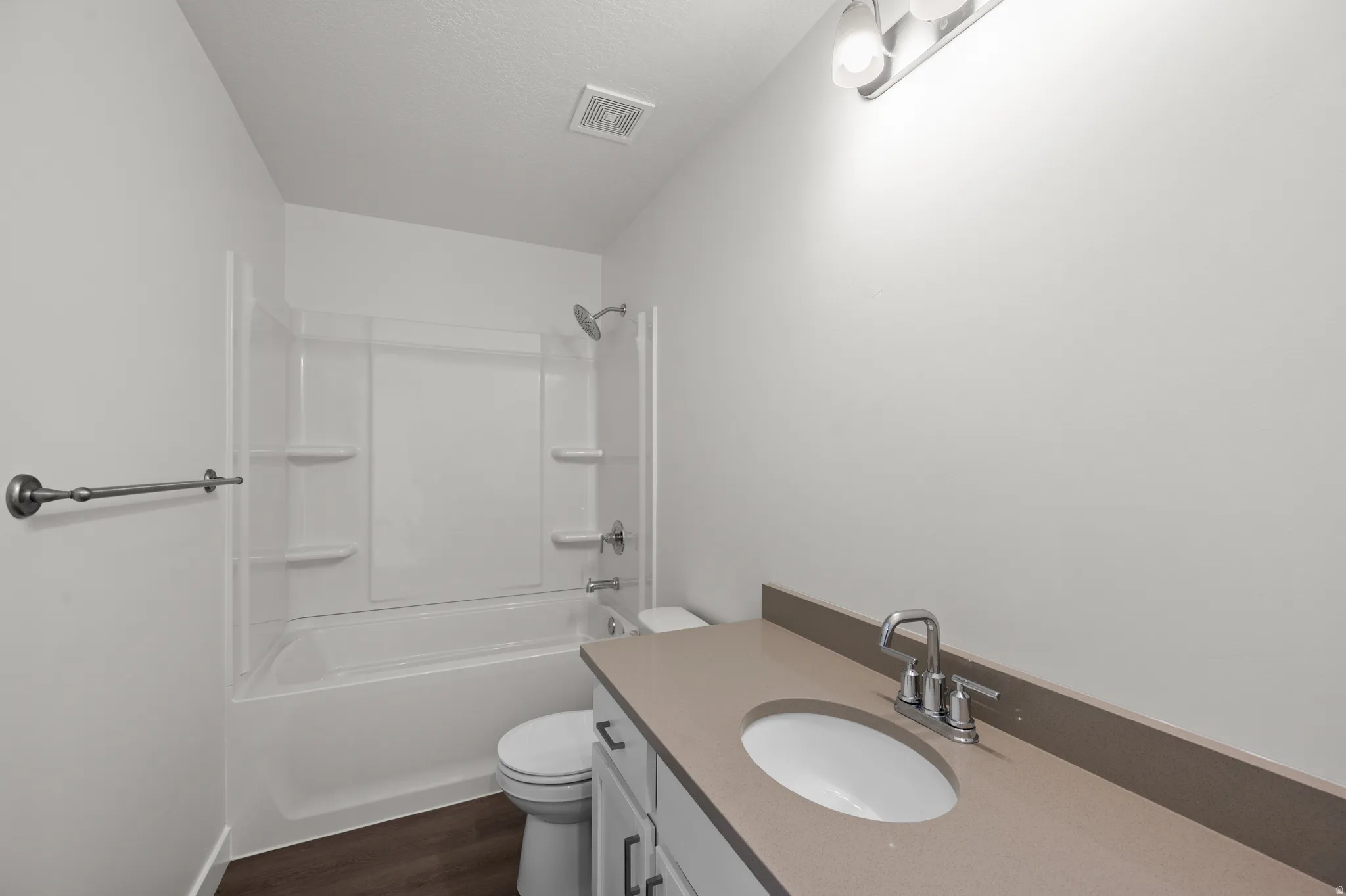 Bathroom featuring vanity, shower / tub combination, dark wood-type flooring, and a textured ceiling