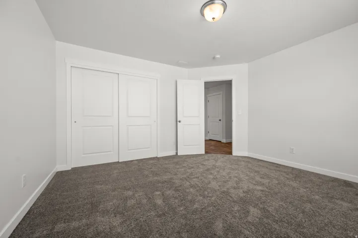 Unfurnished bedroom featuring a closet and dark carpet