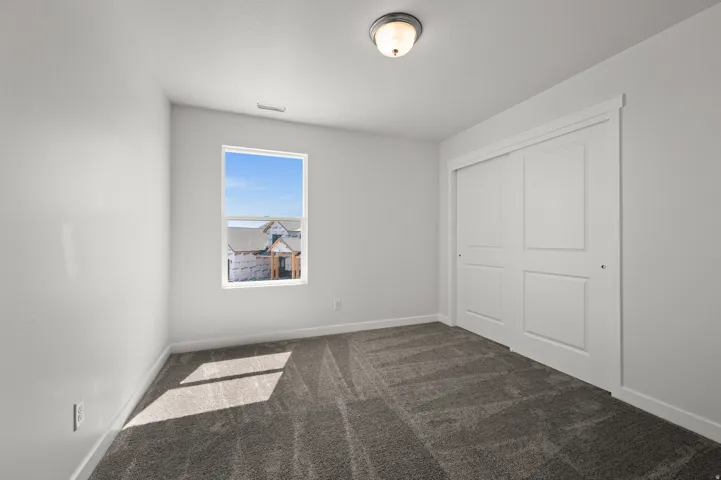 Unfurnished bedroom featuring dark colored carpet and a closet