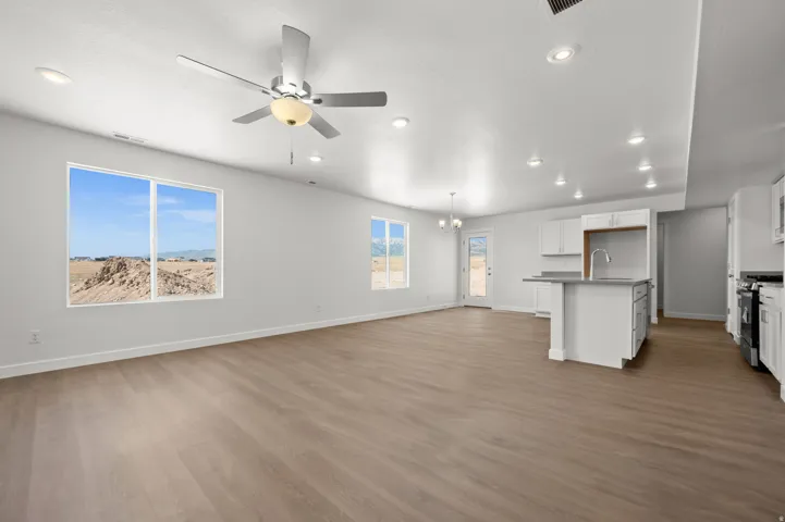 Unfurnished living room featuring a ceiling fan, dark wood-style flooring, and a chandelier