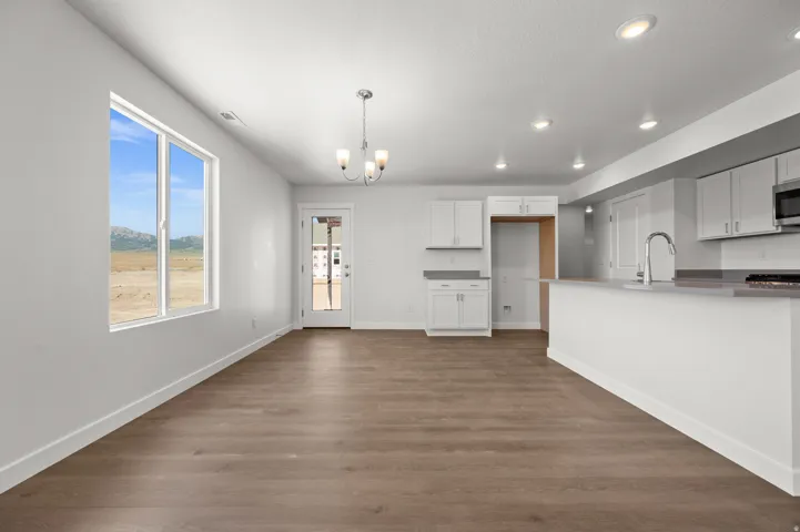 Kitchen featuring hanging lights, white cabinets, dark wood-type flooring, and stainless steel microwave