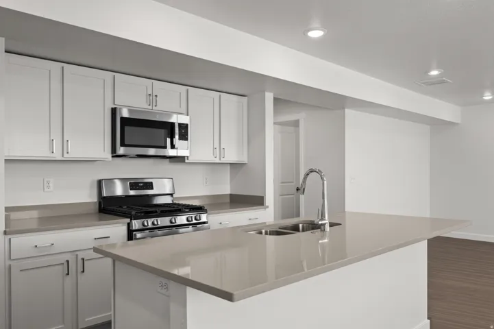Kitchen featuring stainless steel appliances, a kitchen island with sink, white cabinetry, dark wood-style floors, and recessed lighting