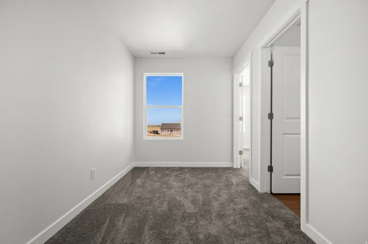 Empty room with dark colored carpet and baseboards