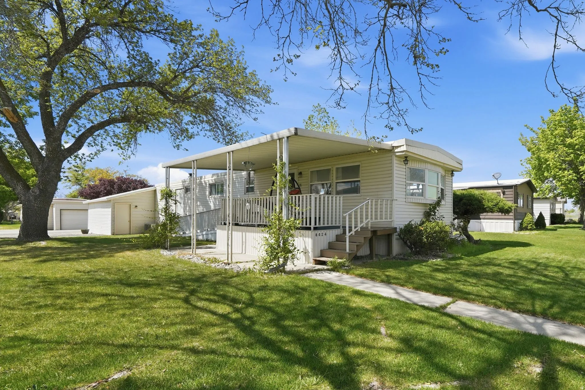 View of front of property with a front lawn, a detached garage, and a wooden deck