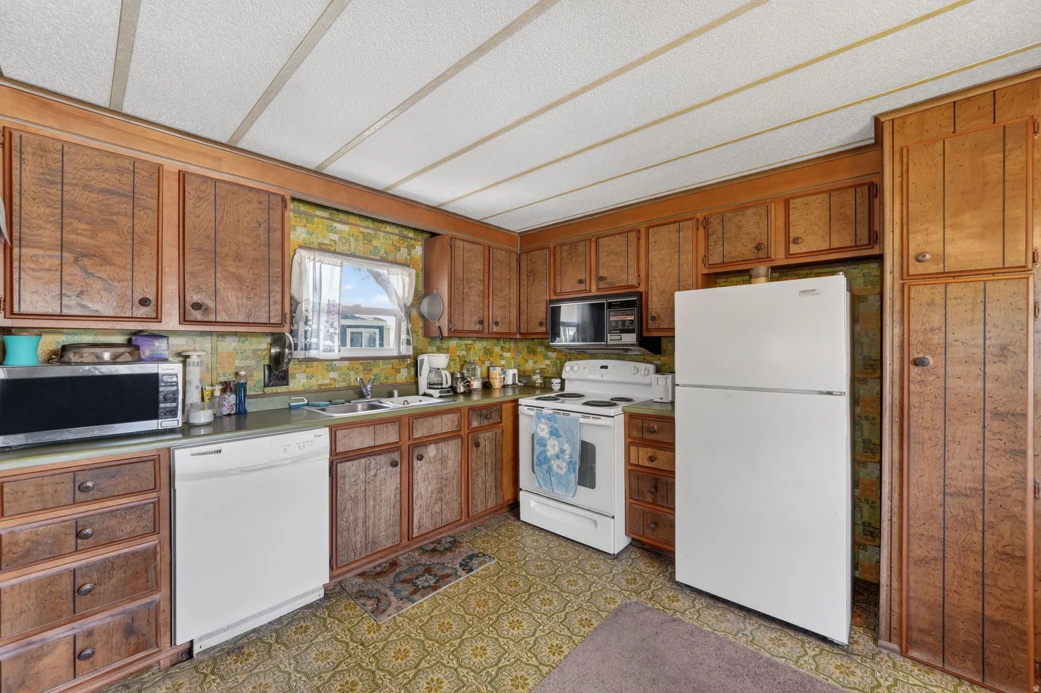 Kitchen with white appliances, wood finish cabinetry, dark floors, and light countertops