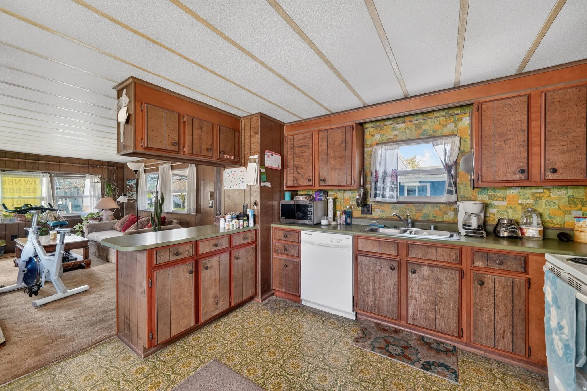 Kitchen with wood finish cabinets, open floor plan, white appliances, healthy amount of natural light, and a textured ceiling