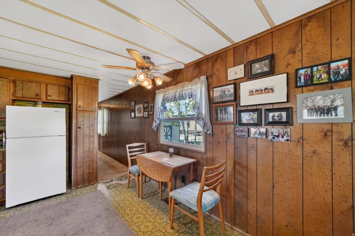 Dining room with wood walls and a ceiling fan
