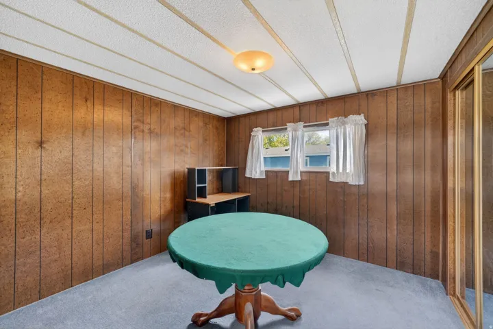 Living area with carpet flooring, wood walls, and a textured ceiling