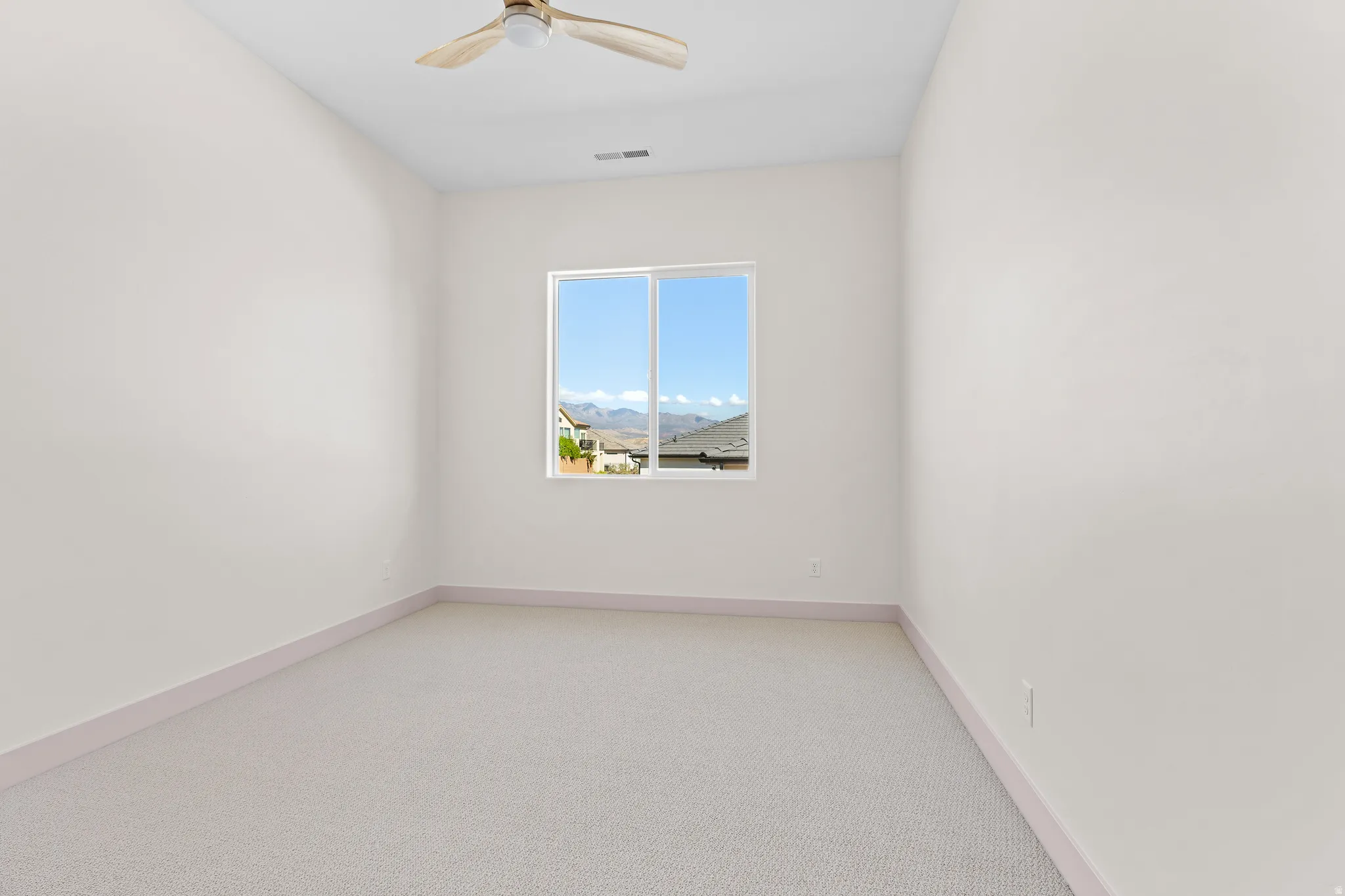 Spare room featuring light carpet and ceiling fan