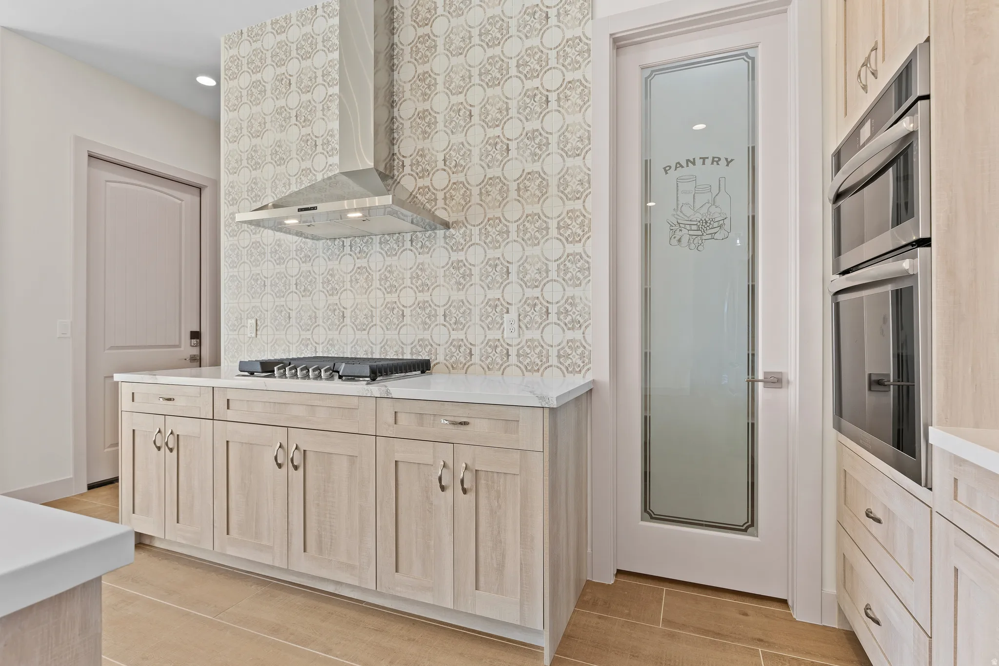 Kitchen with light wood finish cabinetry, stainless steel appliances, backsplash, and light stone countertops