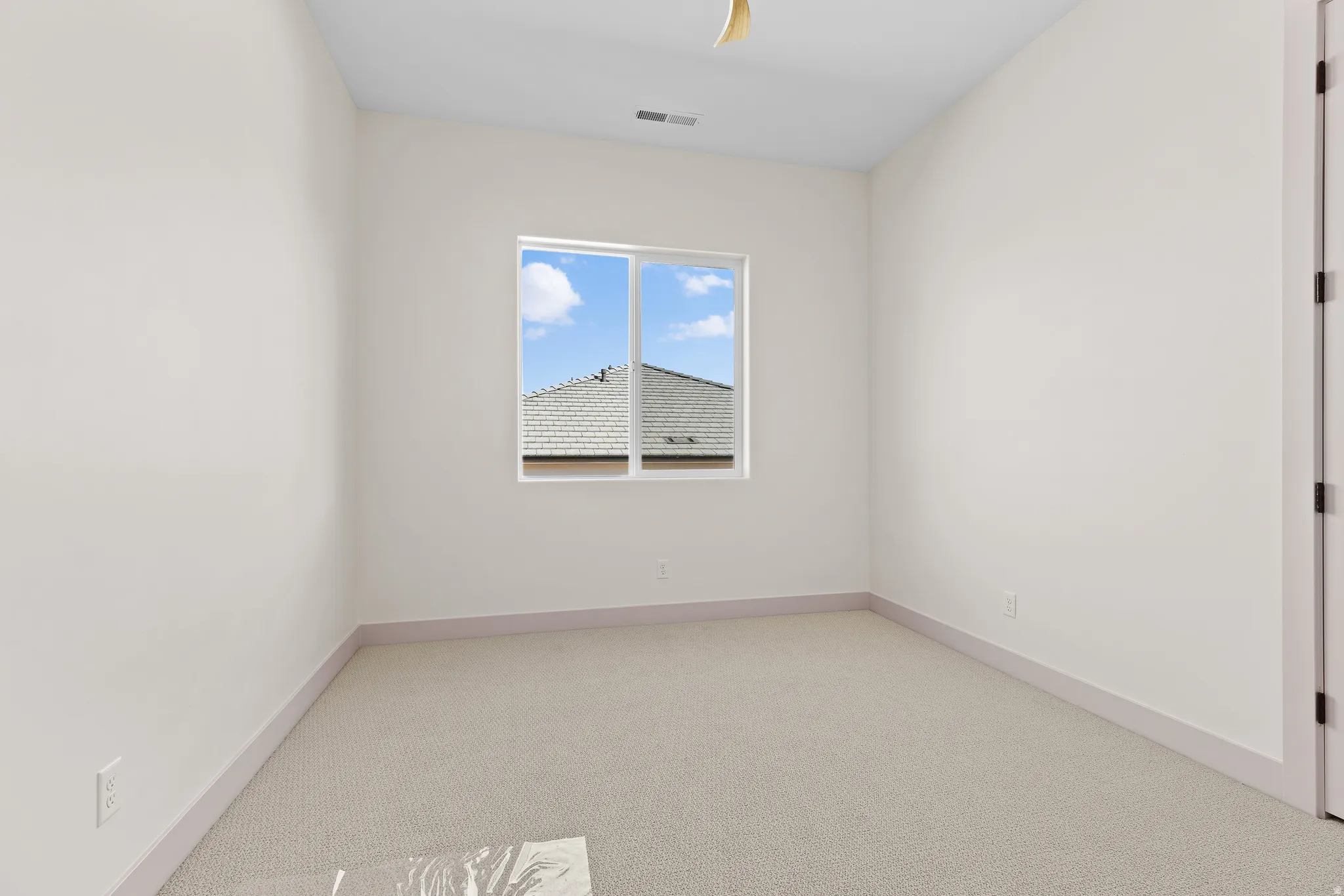 Empty room with light colored carpet and baseboards