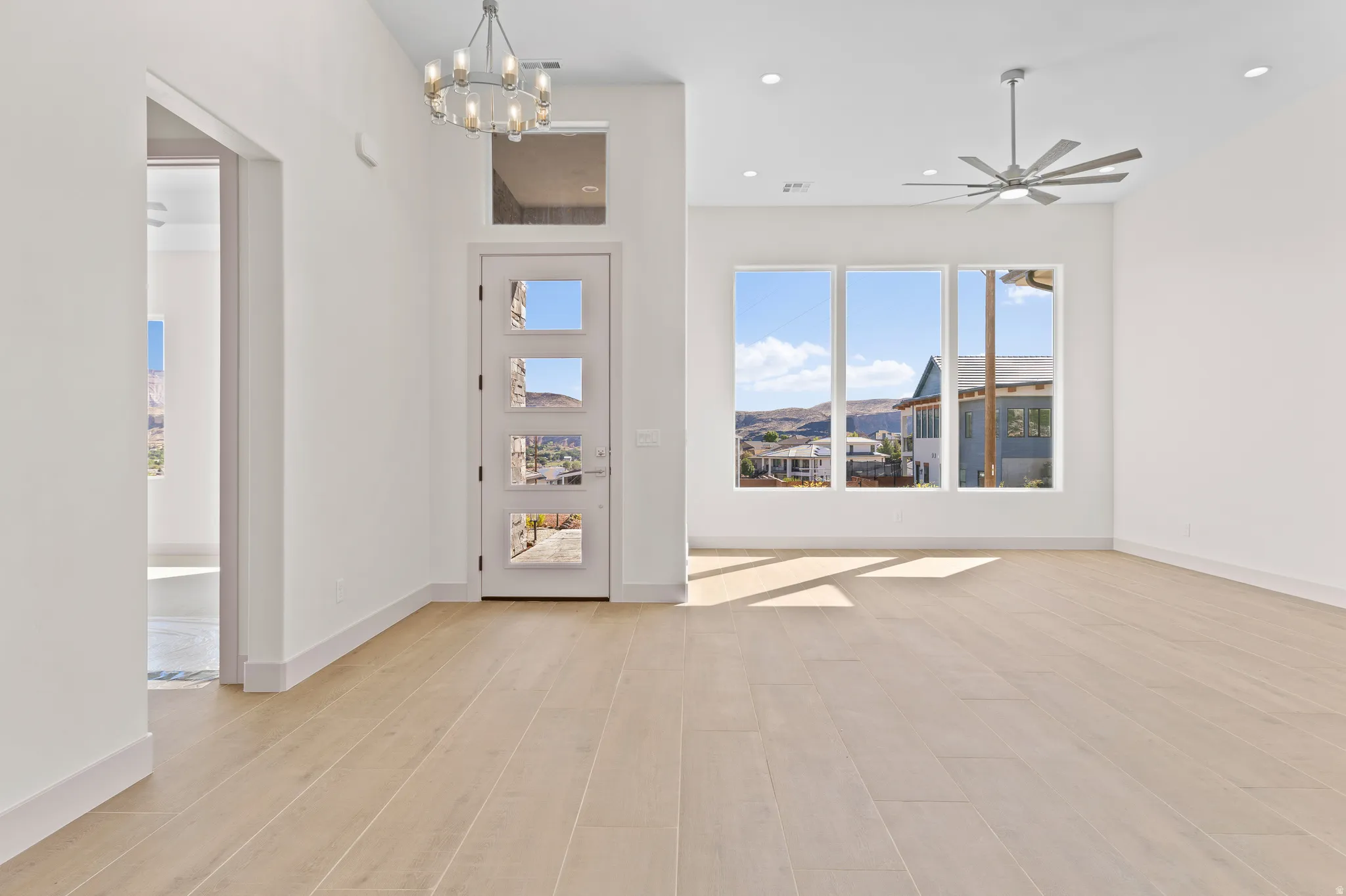 Foyer entrance with suspended lighting, light wood-style flooring, and ceiling fan