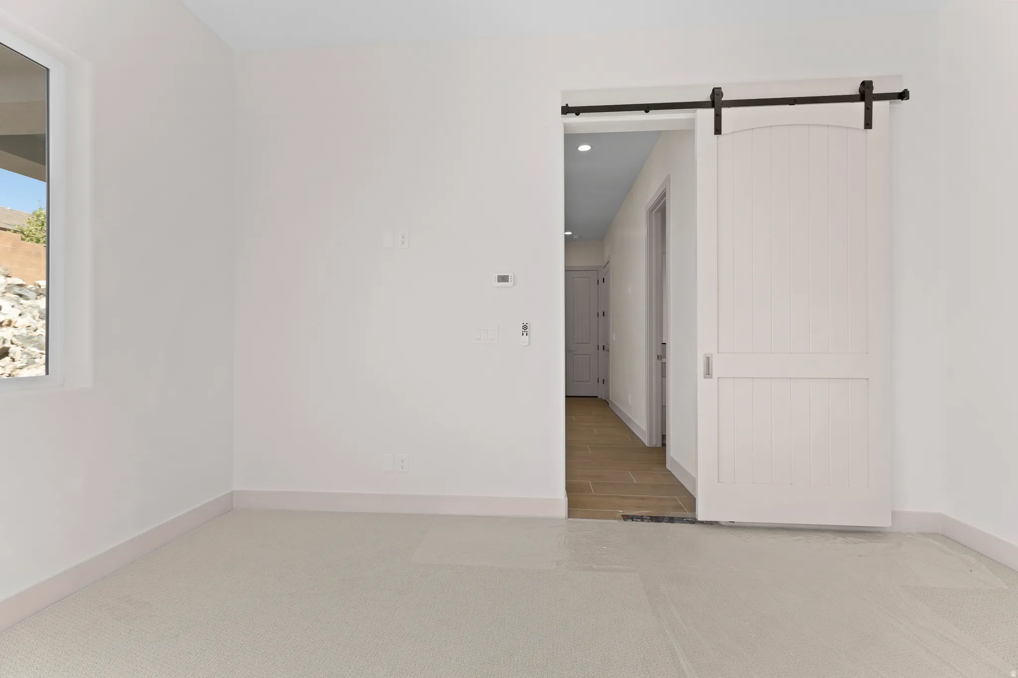 Spare room featuring a barn door, light carpet, and recessed lighting