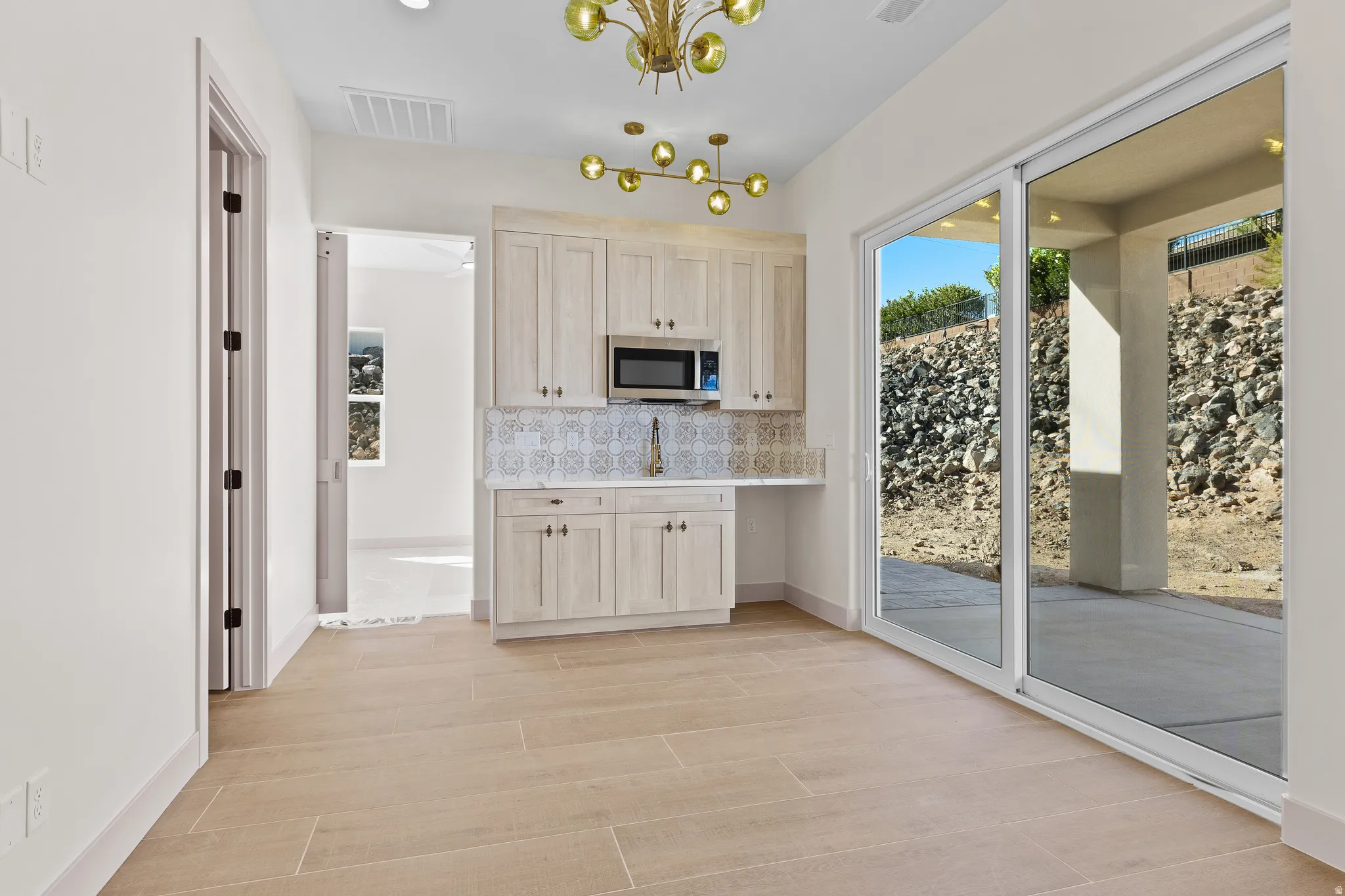 Kitchen featuring stainless steel microwave, hanging lights, healthy amount of natural light, and light wood finish cabinetry