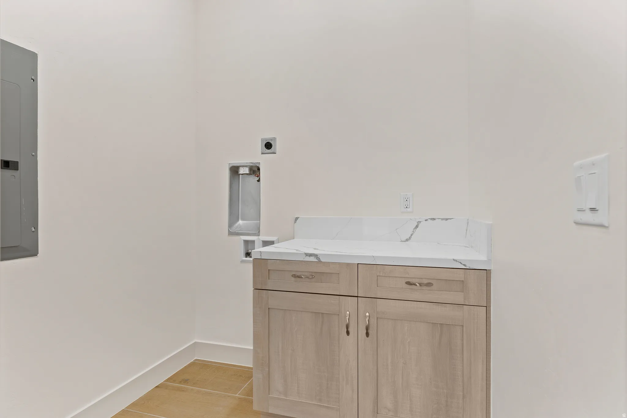 Laundry room featuring electric panel, cabinet space, washer hookup, and light wood-style flooring