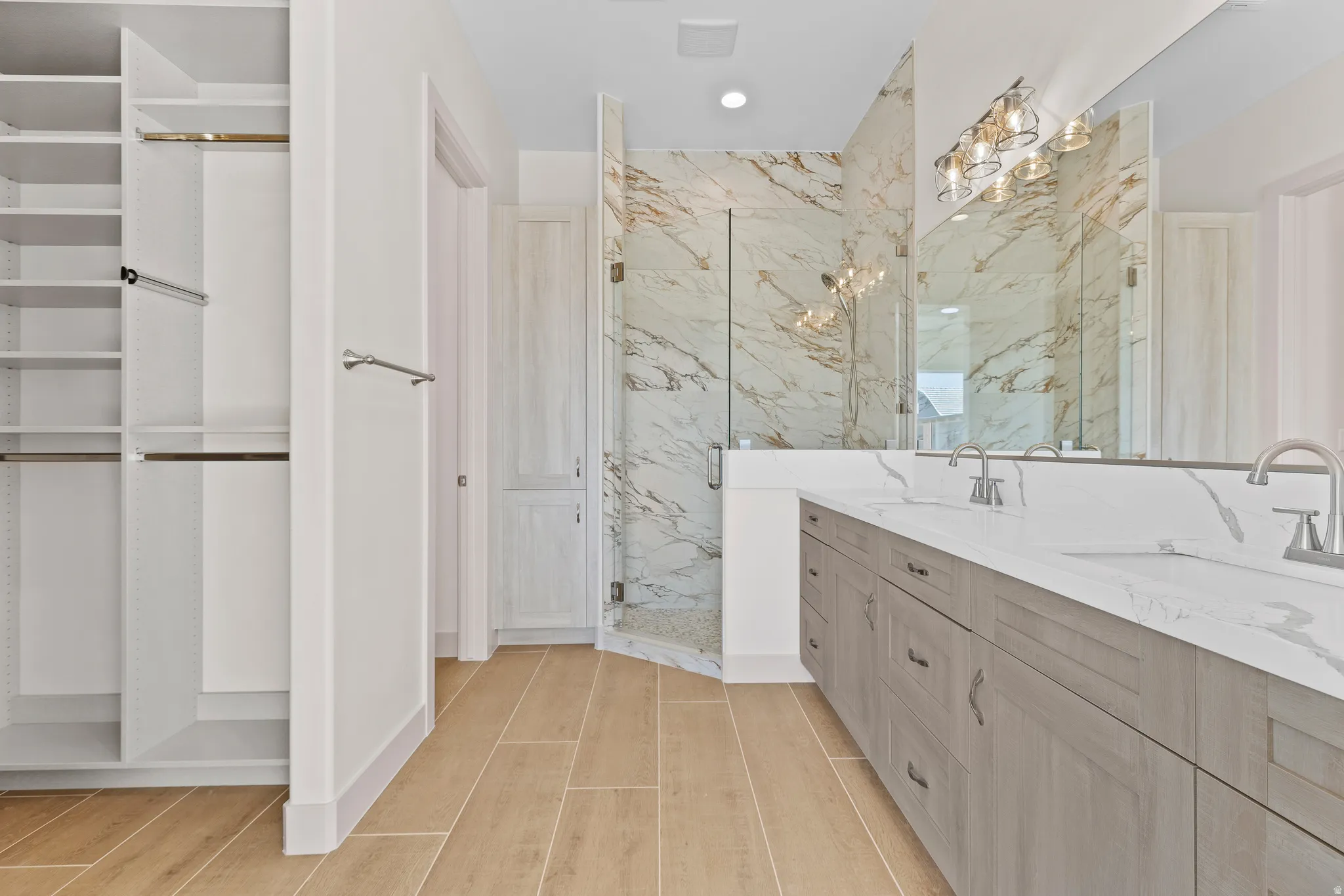 Full bath featuring double vanity, a marble finish shower, and wood tiled floors