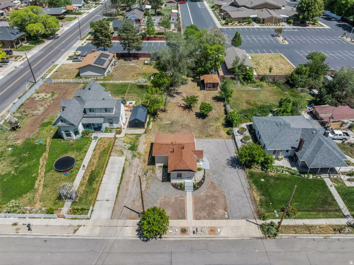 Aerial perspective showcasing a property with a light-colored exterior and a brown shingle roof, positioned between two neighboring residences
