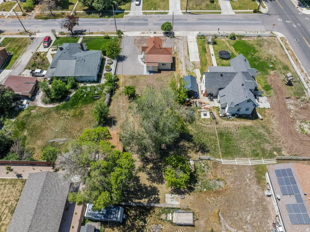 Expansive property with a significant land parcel, featuring mature trees and a white picket fence bordering a portion of the perimeter