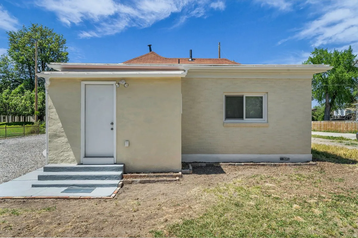 Exterior wall featuring a light-colored finish and a white entry door
