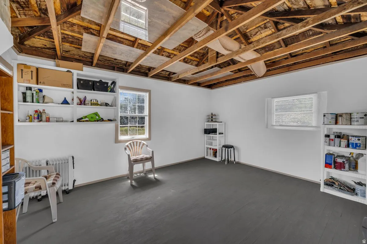Room featuring exposed wood ceiling beams, white walls, and dark flooring