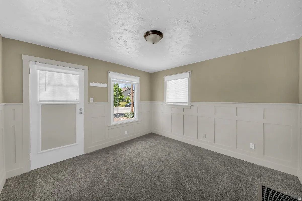 Interior space featuring light gray textured carpeting and white wainscoting