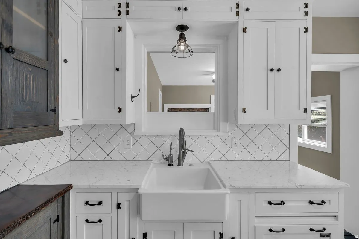 Kitchen featuring a white farmhouse sink, white countertops, and white subway tile backsplash with dark grout