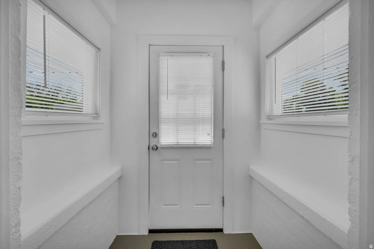 Entryway featuring a white door with a window, two side windows with blinds, and white painted walls with a textured lower half