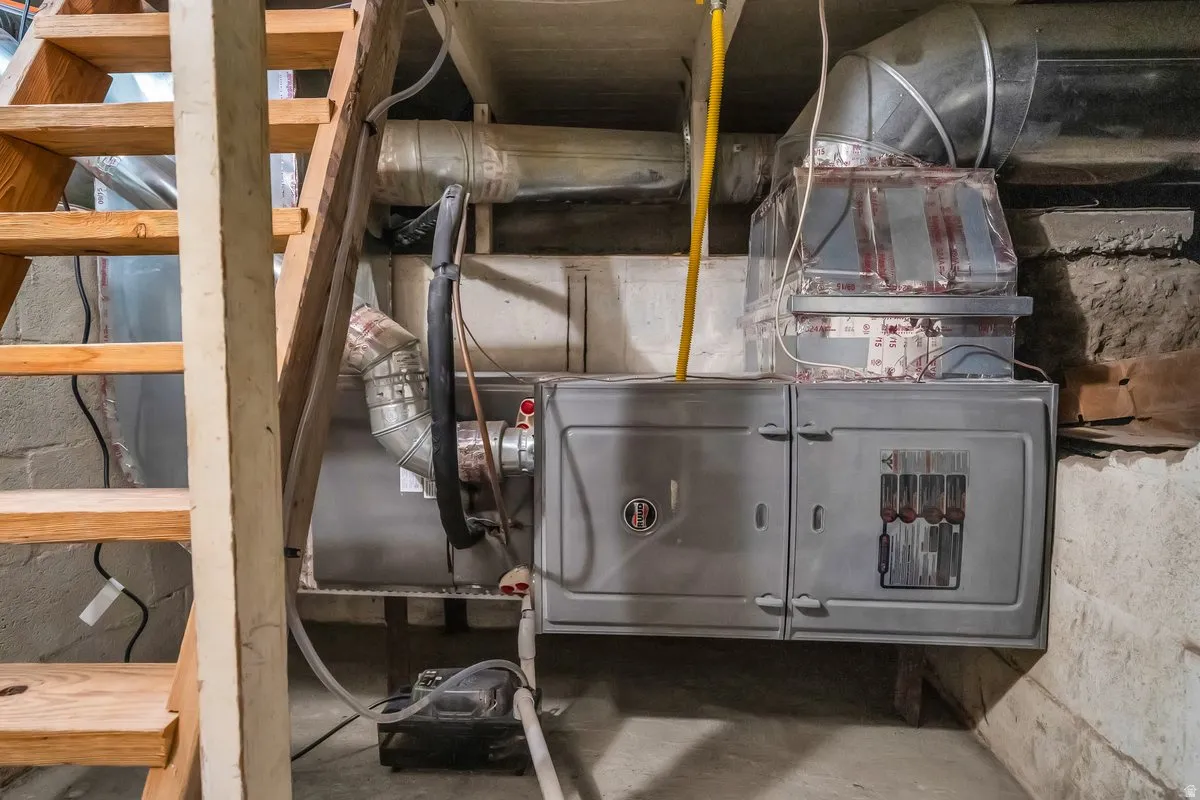 Mechanical room with a forced-air furnace, exposed ductwork, and an electrical panel