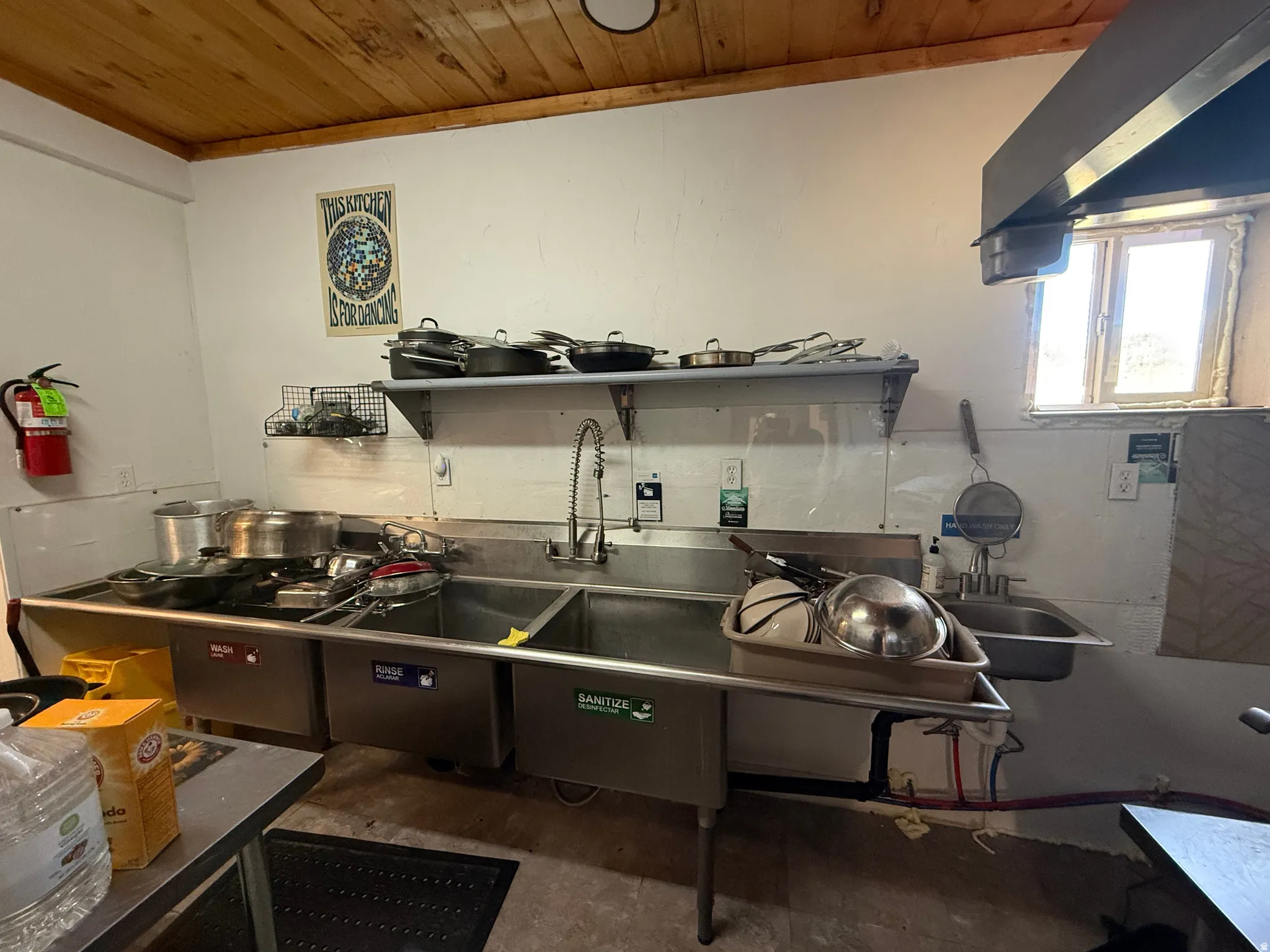 Commercial-grade stainless steel three-compartment sink with an integrated sprayer faucet