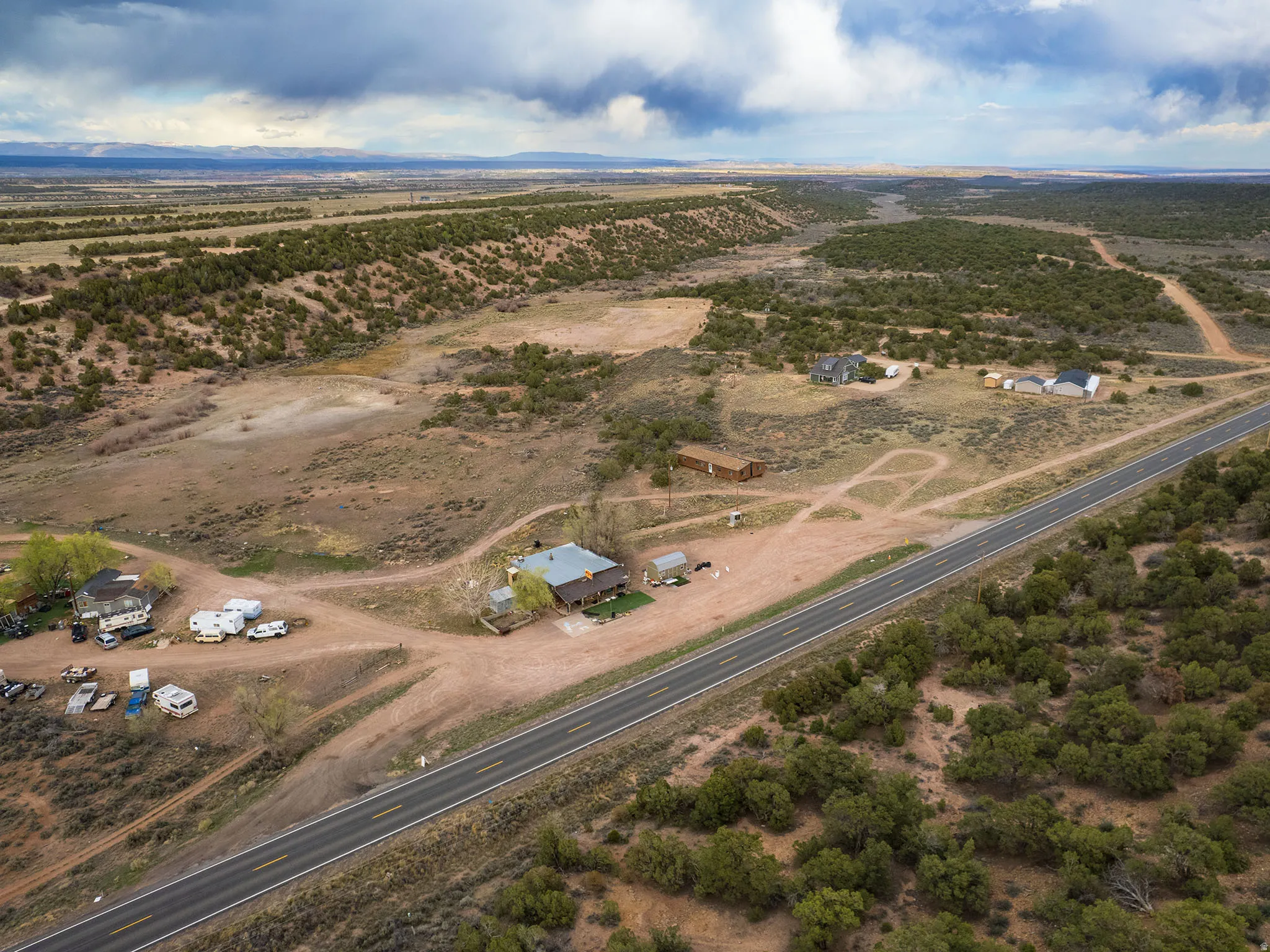 Expansive rural landscape featuring multiple structures, a paved roadway, and natural desert vegetation