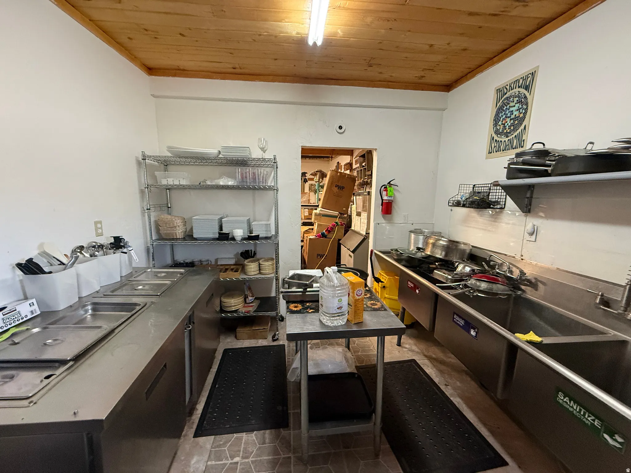 Commercial kitchen featuring stainless steel countertops, multiple sinks, and a wood-finish ceiling