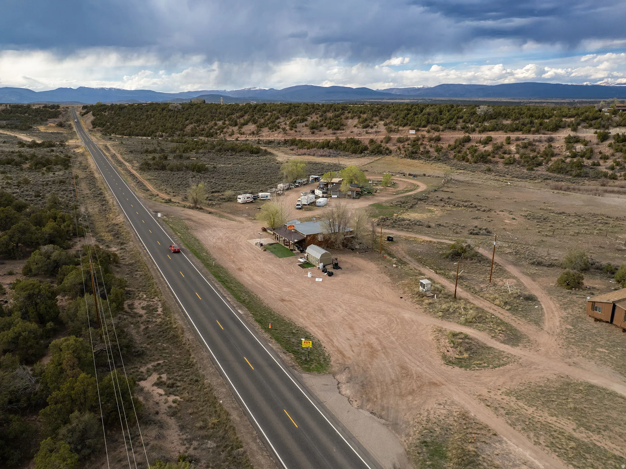 Rural property featuring a long paved road frontage, natural landscaping, and distant mountain ranges