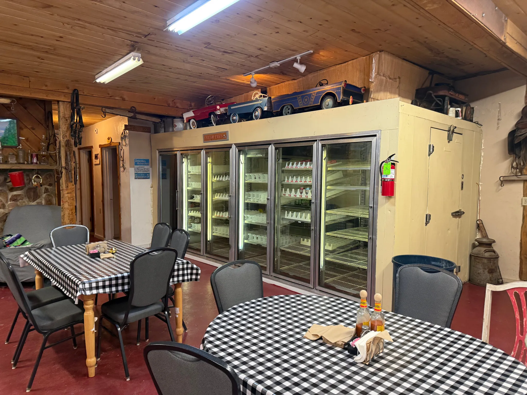 Commercial space featuring a wood-panel ceiling, four glass-front refrigerators, a walk-in cold storage unit, and a stone-faced partial wall