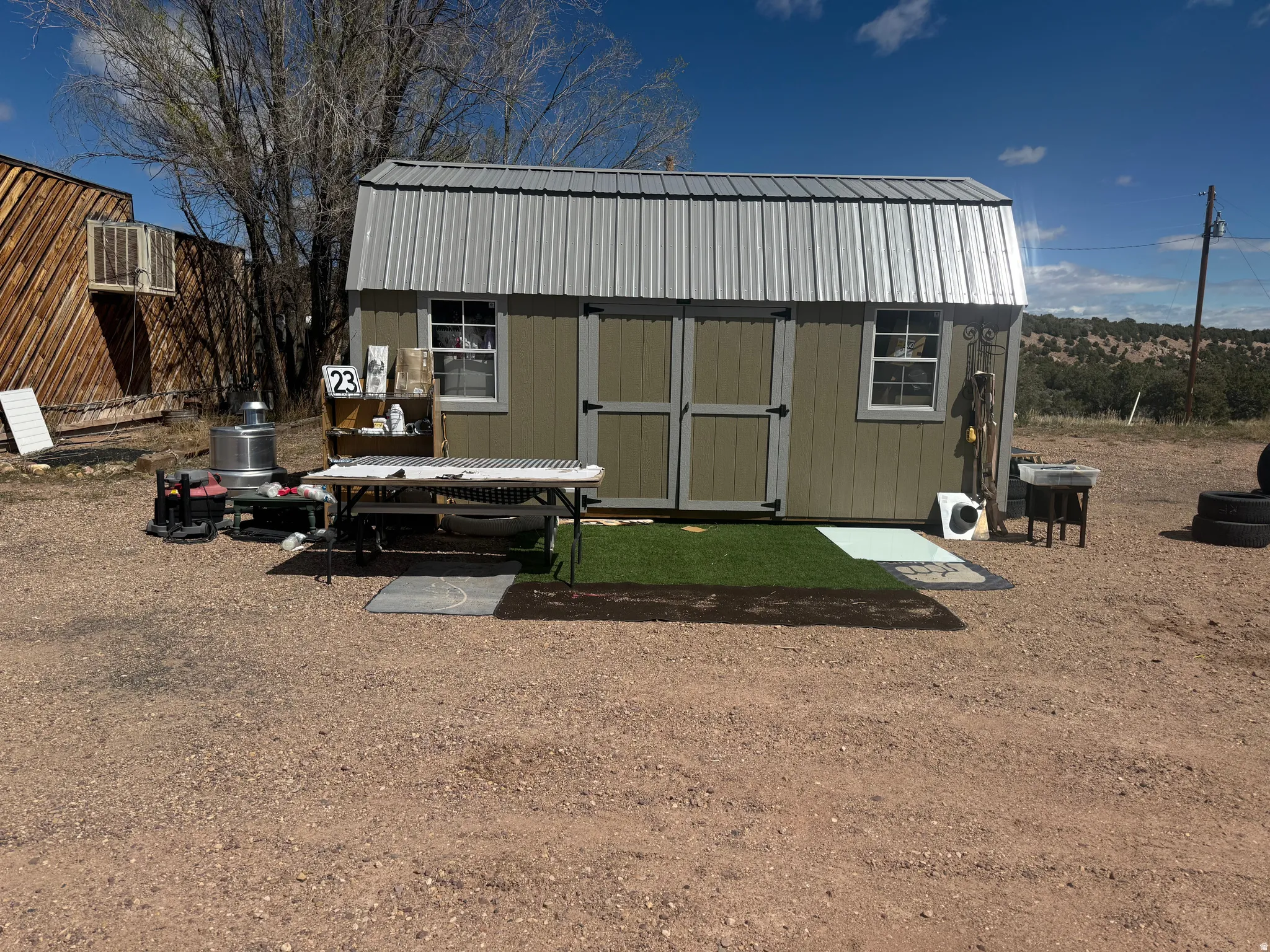 Detached utility building featuring a corrugated metal roof, neutral-toned siding, and double entry doors