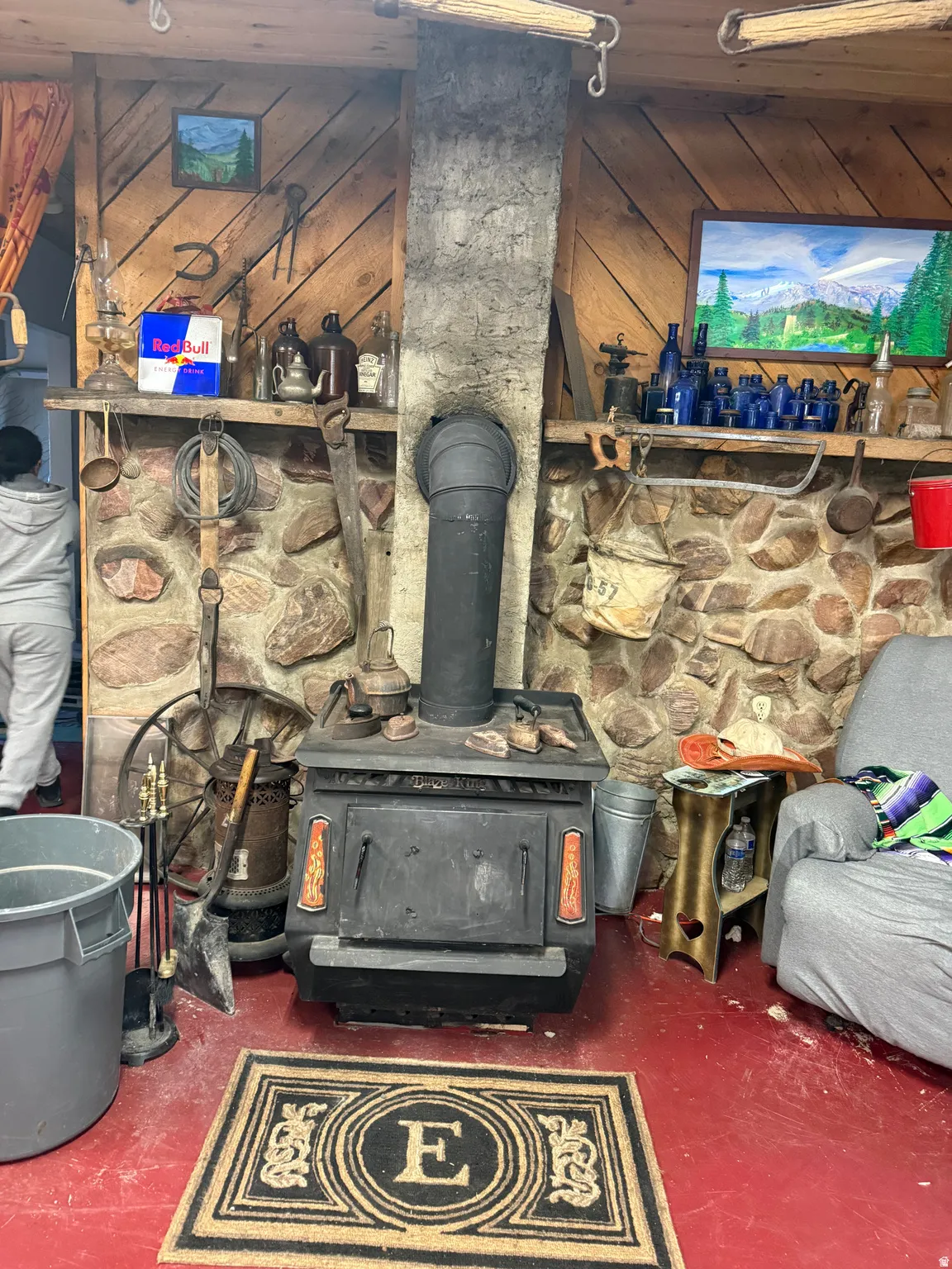 Freestanding black wood-burning stove with a matching stovepipe against a stone wall