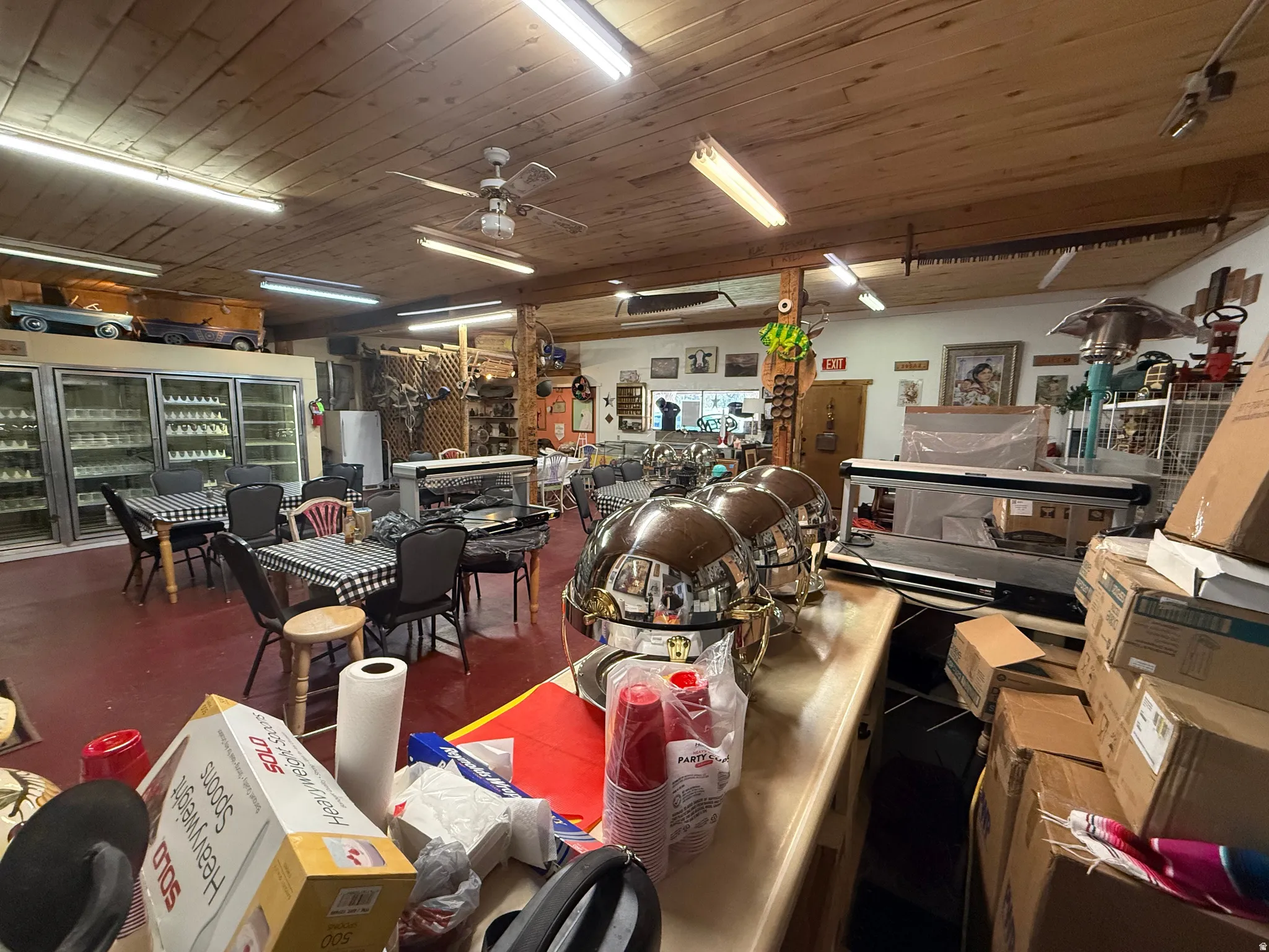 Spacious interior with exposed wood-plank ceiling, ceiling fans, and fluorescent lighting