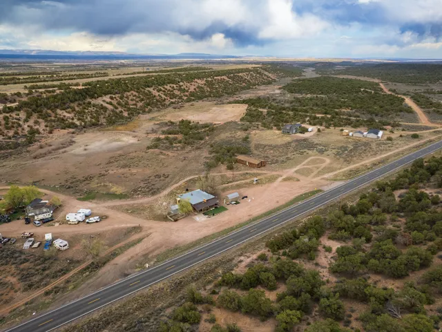 Expansive rural landscape featuring multiple structures, a paved roadway, and natural desert vegetation