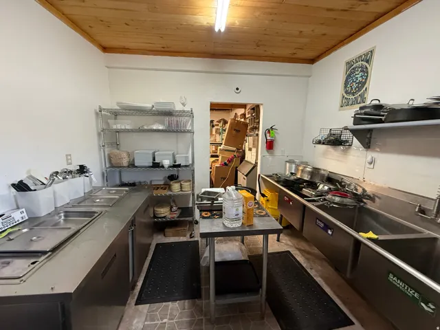 Commercial kitchen featuring stainless steel countertops, multiple sinks, and a wood-finish ceiling