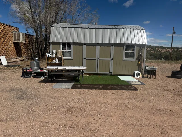 Detached utility building featuring a corrugated metal roof, neutral-toned siding, and double entry doors