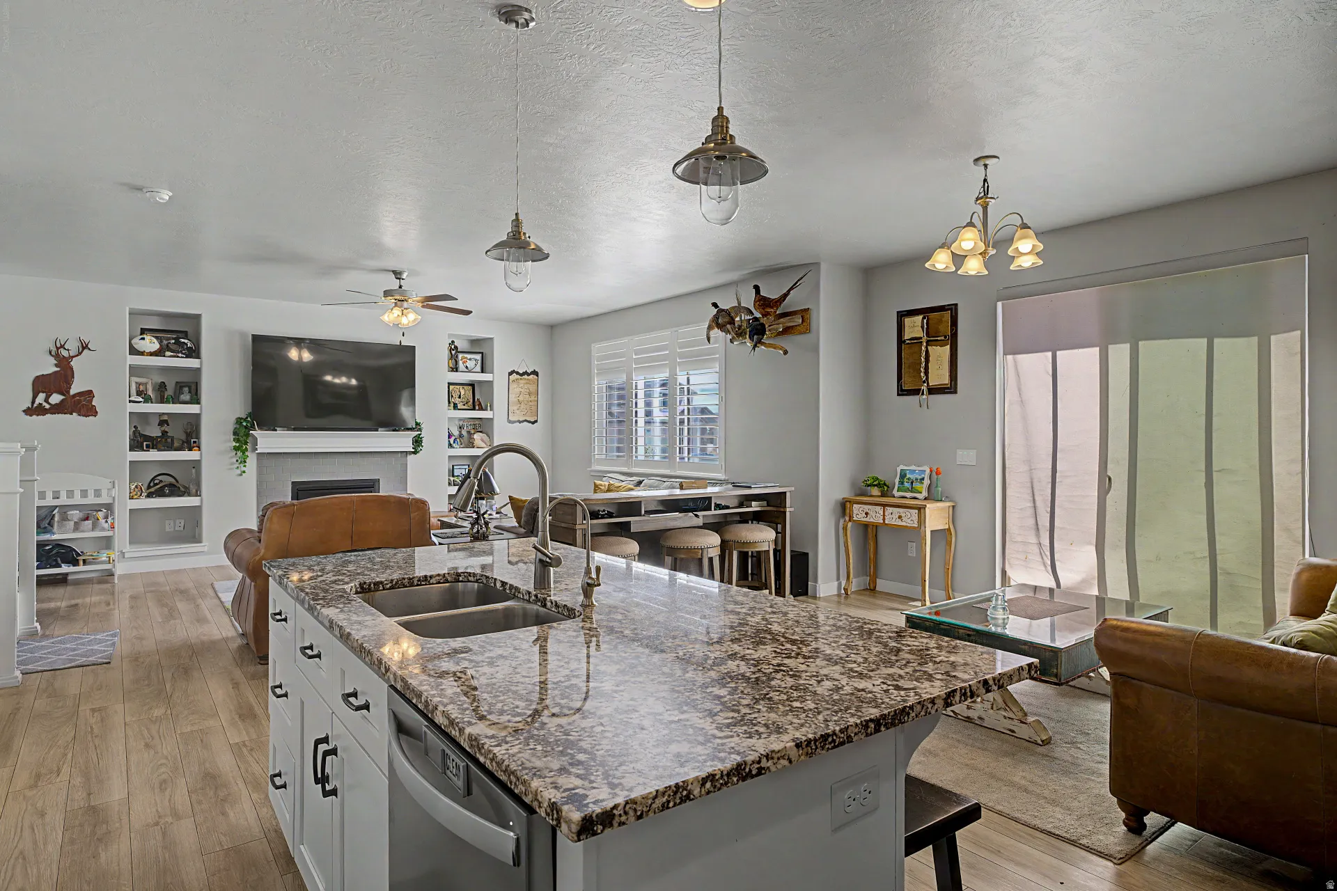 Kitchen with open floor plan, a kitchen bar, a fireplace, light wood-style flooring, and a textured ceiling
