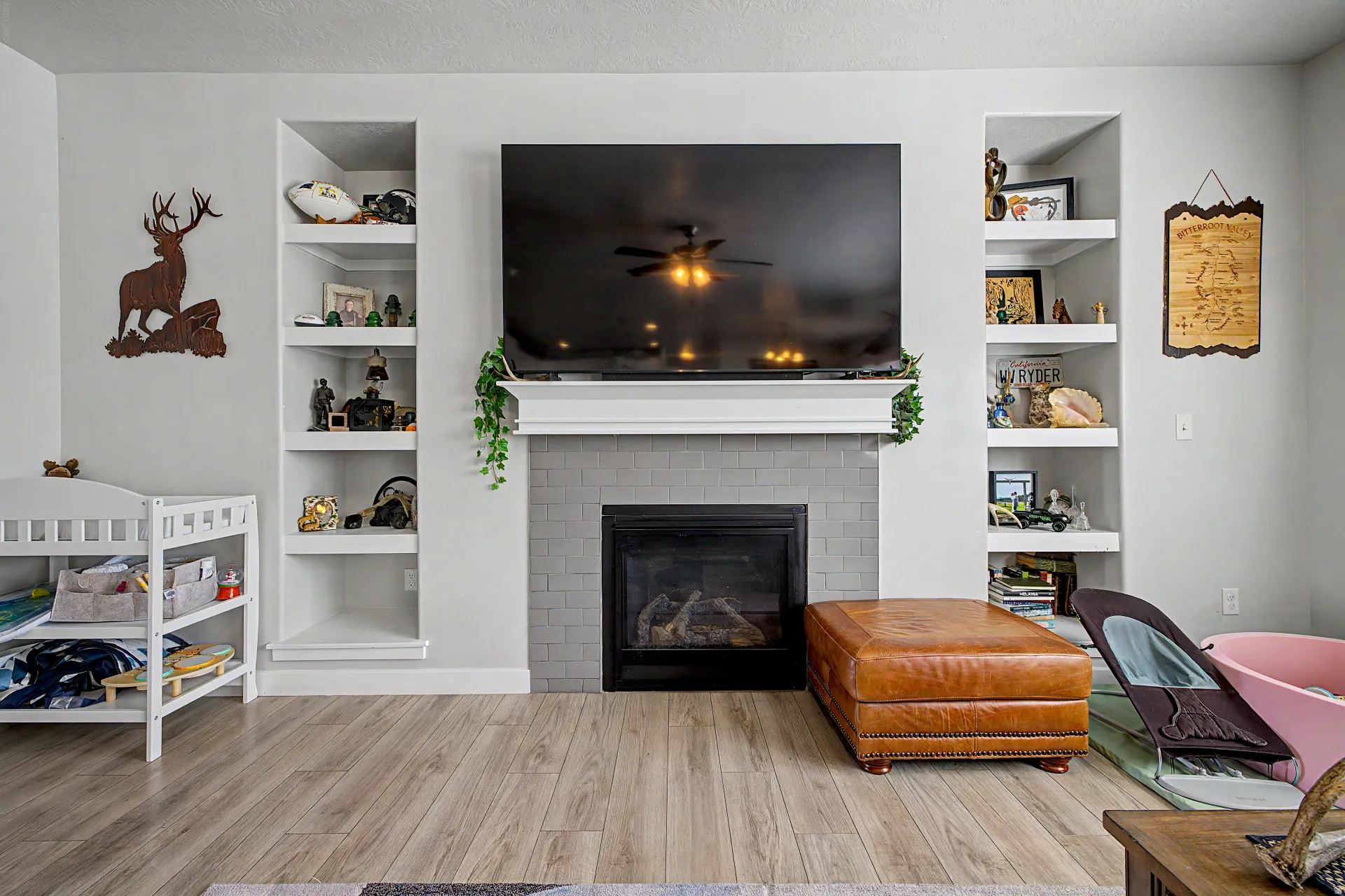 Living room featuring built in shelves, light wood-style flooring, a brick fireplace, and ceiling fan