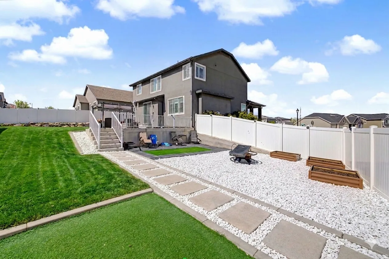 Ai enhanced  Tiered backyard featuring a large green lawn, a white PVC privacy fence, and a patio with an attached deck