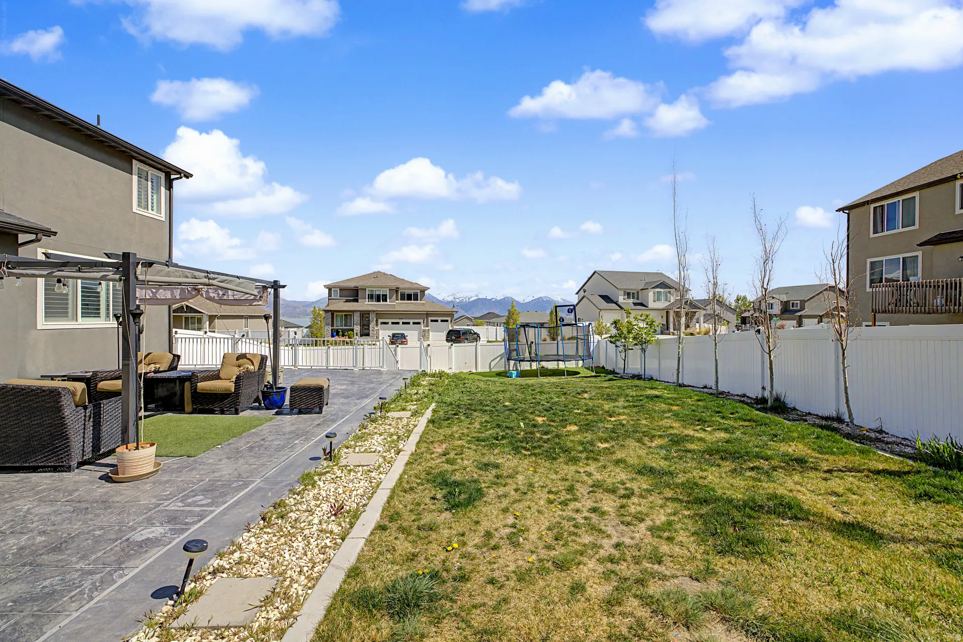 Fenced backyard featuring a trampoline, a residential view, a patio area, and an outdoor hangout area
